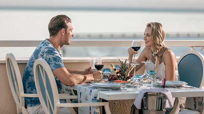 Young lovely couples eating lunch and drinking with romance on seaside balcony